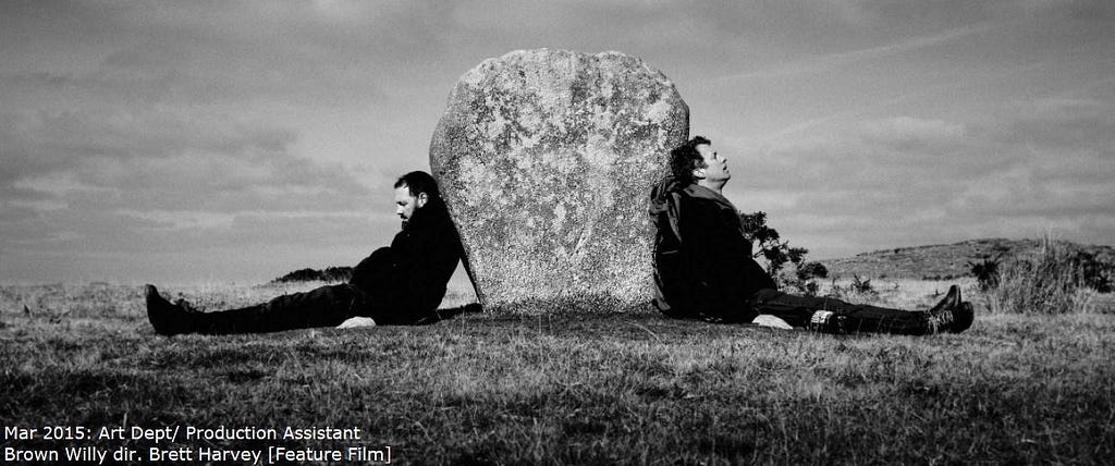 Production image of Brown Willy feature film — 2 men leaning against a rock.