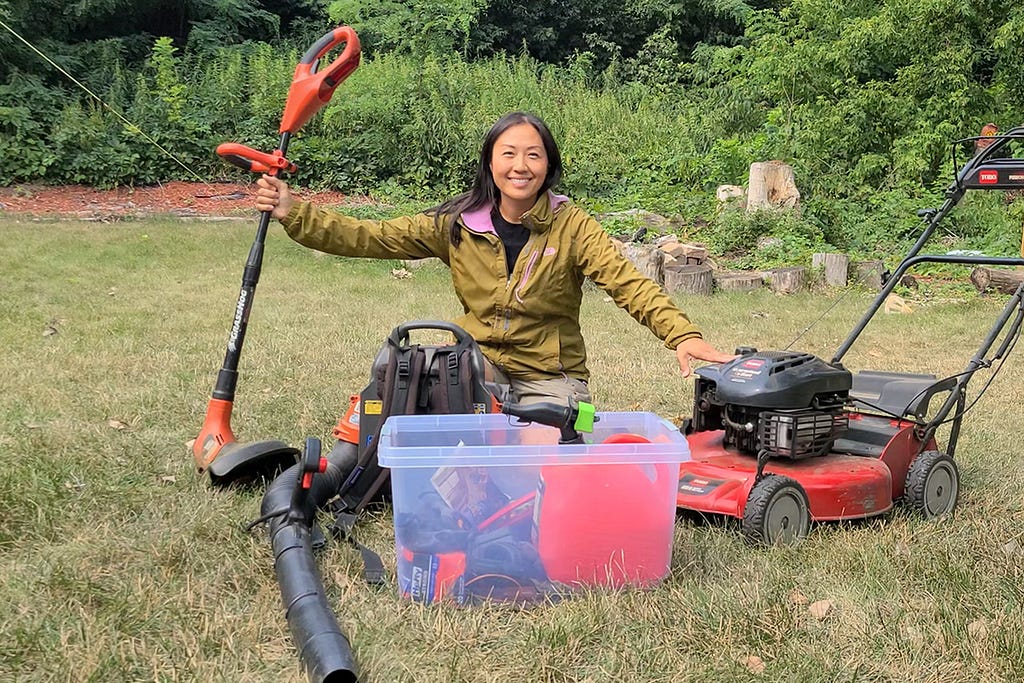 lawnup lady founder sits on grass with lawn mowing equipment