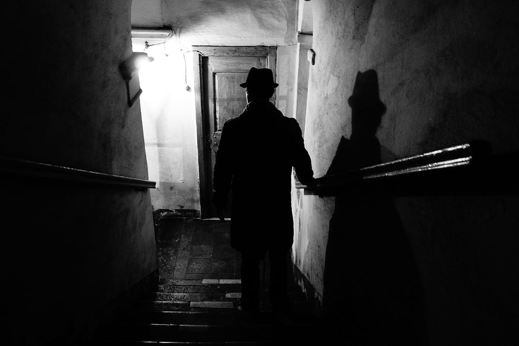 noir-style photograph of a figure descending a staircase