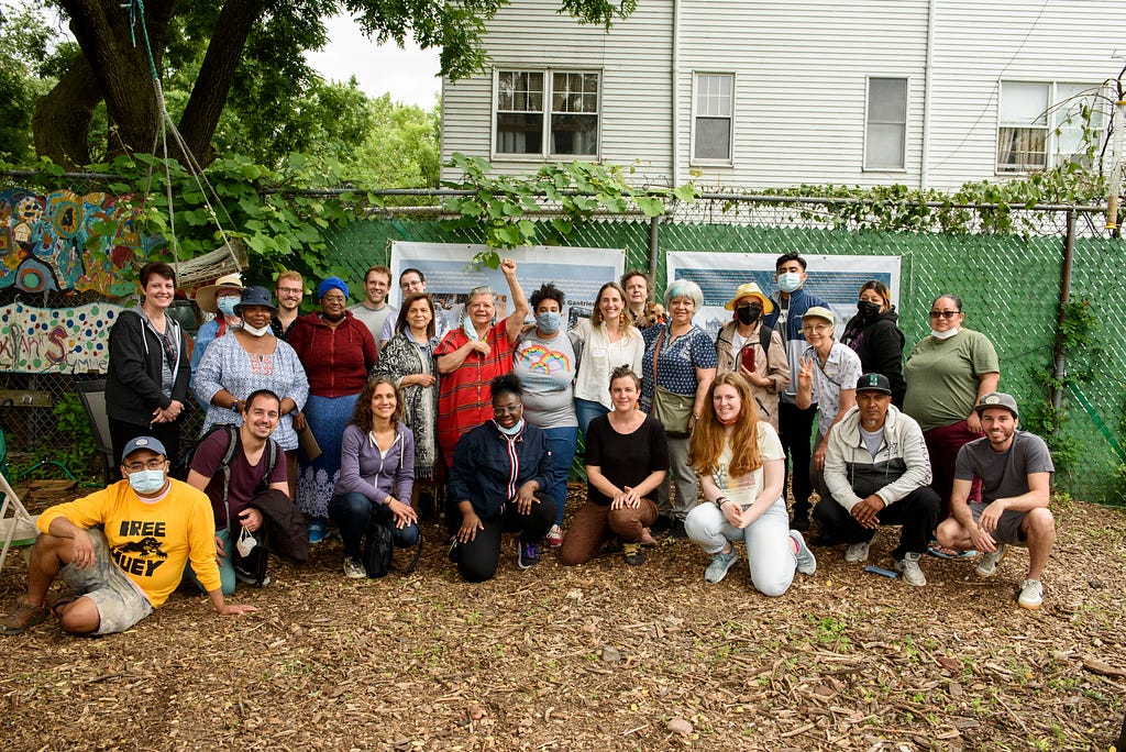 Group photo in front of two banners, hung on a fence in the park