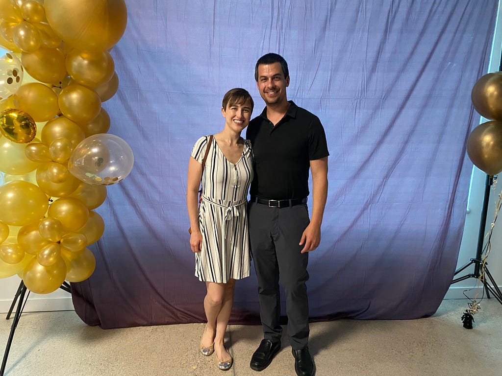 A couple standing in between golden balloons