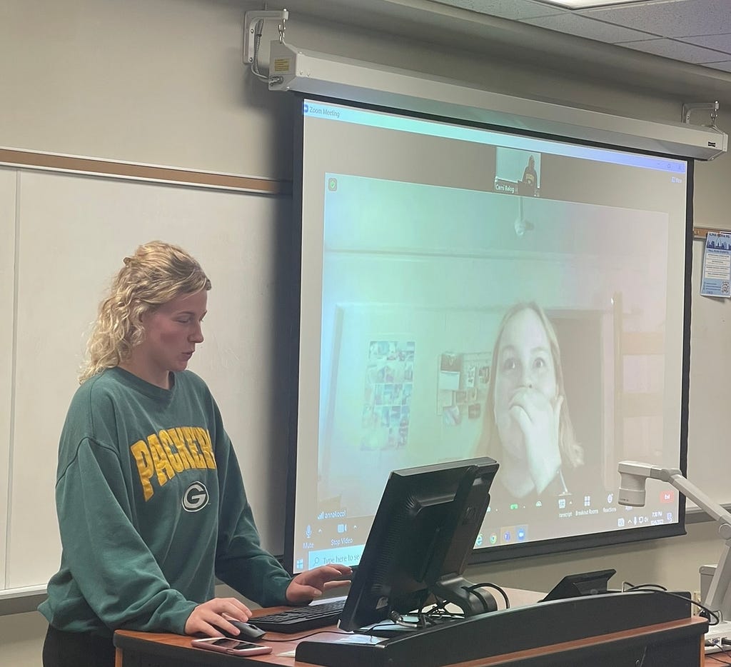 One student talks to another student via zoom and the student on zoom is reacting enthusaiastically.