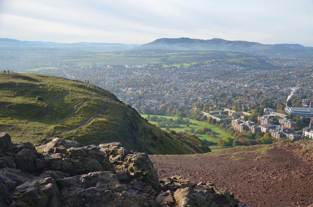 Standing atop a green hill, overlooking the city of Edinburgh.