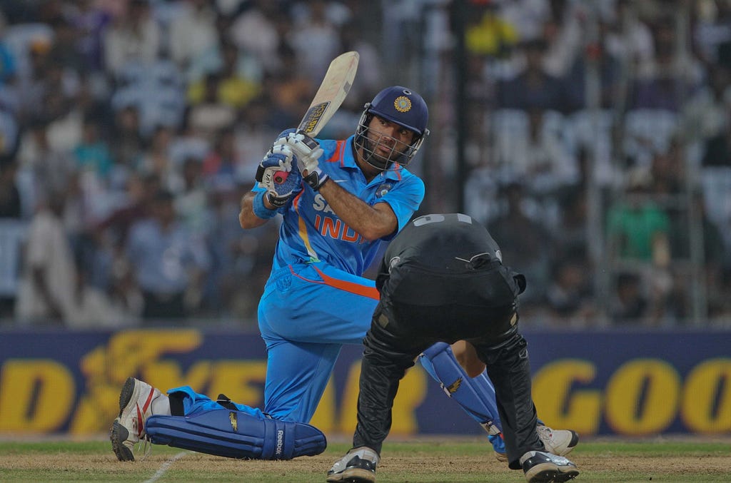 Left-handed cricket batsman hitting the ball as the opposition player ducks to save himself.