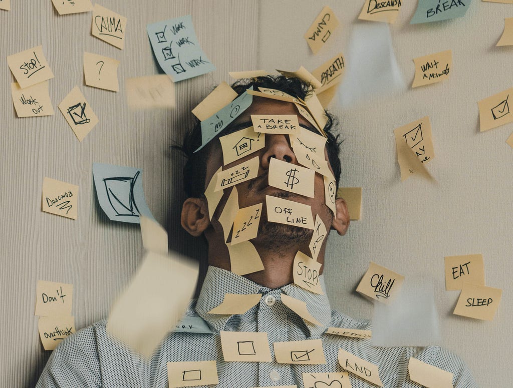 A man in the corner with to-do sticky notes all over him