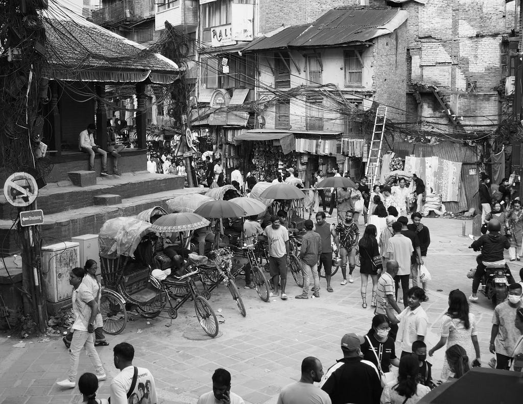 A busy intersection with bicycle rickshaw taxis in the heart of Kathmandu.