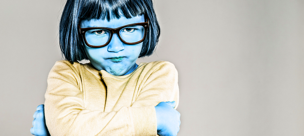 A little girl crosses her arms and pouts. She looks extremely stubborn and defiant.