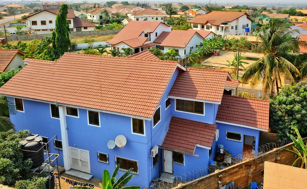 Residential area in West Africa. Top view on family houses, yards with gardens, surrounded by fences & roads. Modern lifestyle in developing countries. Beautiful urban landscape. Ghana, Accra, Tema