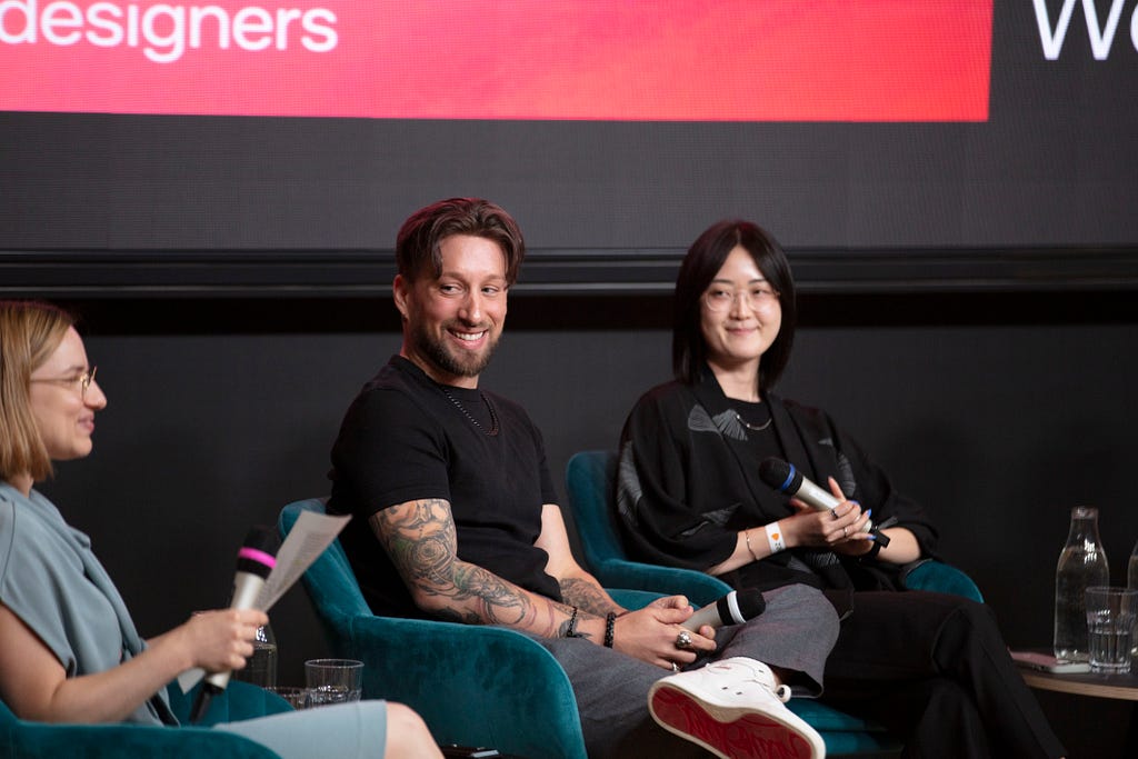 A candid moment with three people, seated in chairs and smiling.