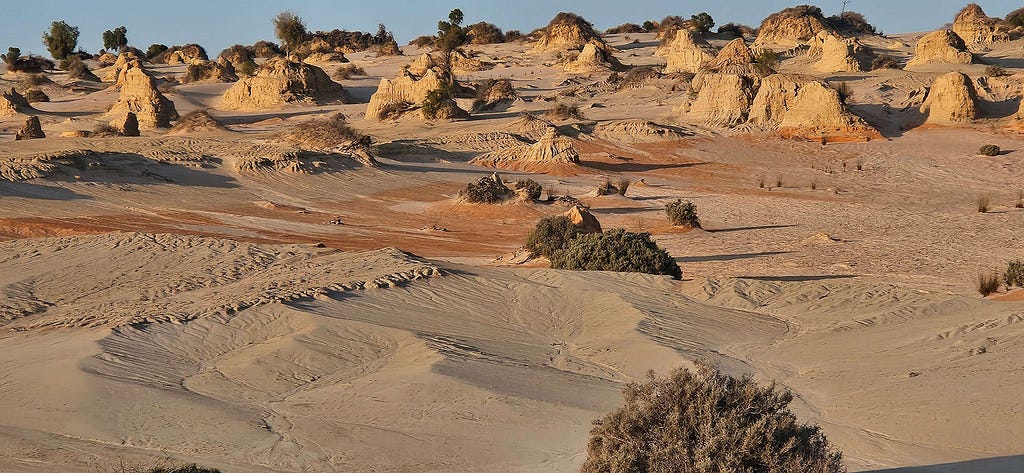 spires and mounds of hardened calcrete sands rising from sand drifts coloured ochre red