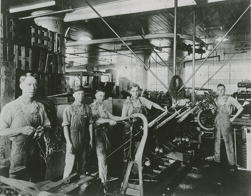 Grease-stained factory workers building engines, circa 1925