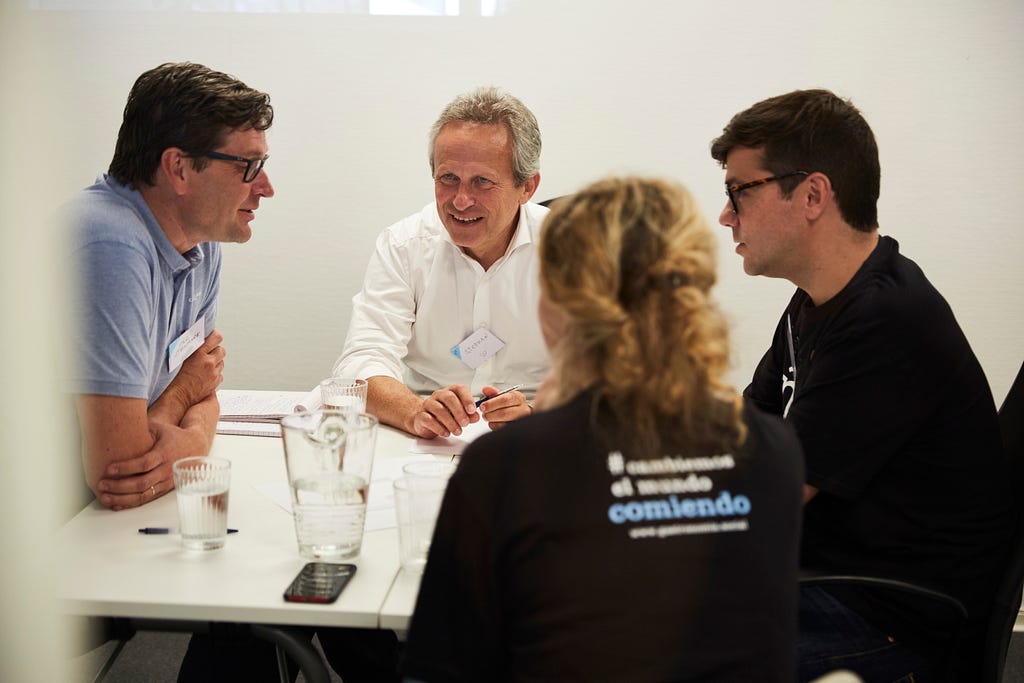 Ashoka Fellow Rafael Rincón, Founder of Fundación Gastronomía Social, and Co-founder of the Social Gastronomy Movement, Nicola Gryczka, together with IKEA co-workers at the Dela Summit 2023 in Älmhult, Sweden. The four people are sitting around a table inside and conversing.