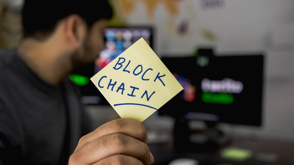 Man holding card that says blockchain