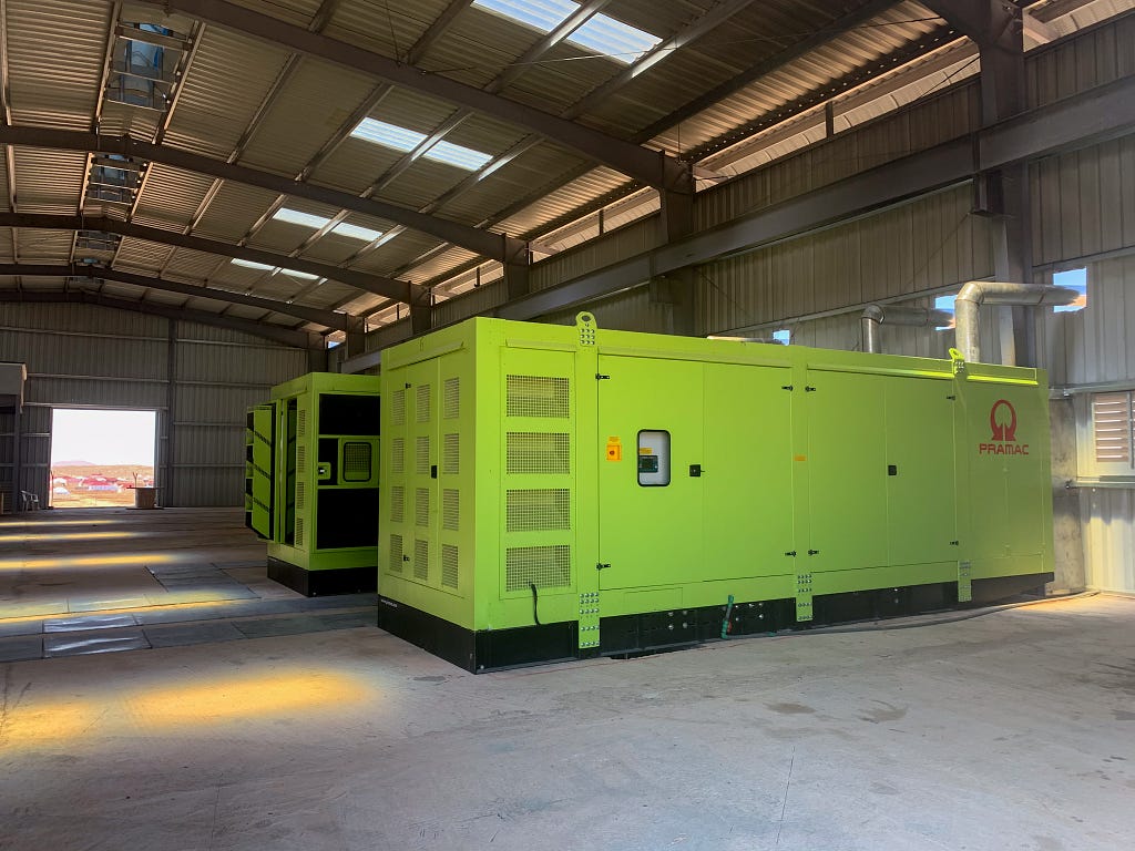 Two large, bright green generators in a warehouse.