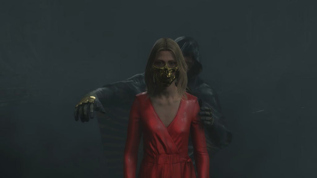 Amelie in her red dress. She wears Higgs’ golden skull mask, while Higgs stands behind her, controlling her movements and speech.