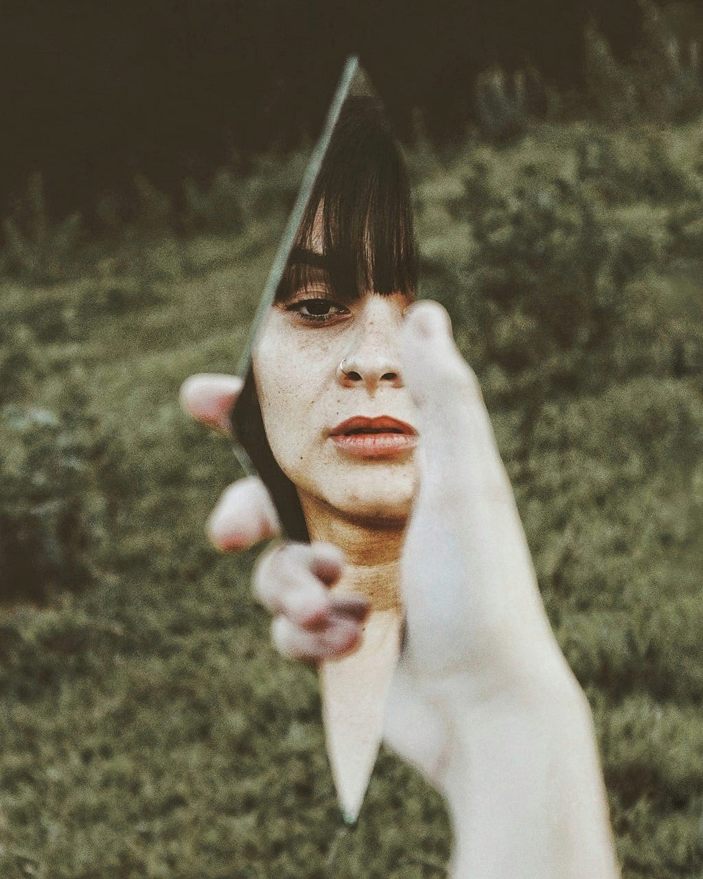 Woman looking into a piece of broken mirror