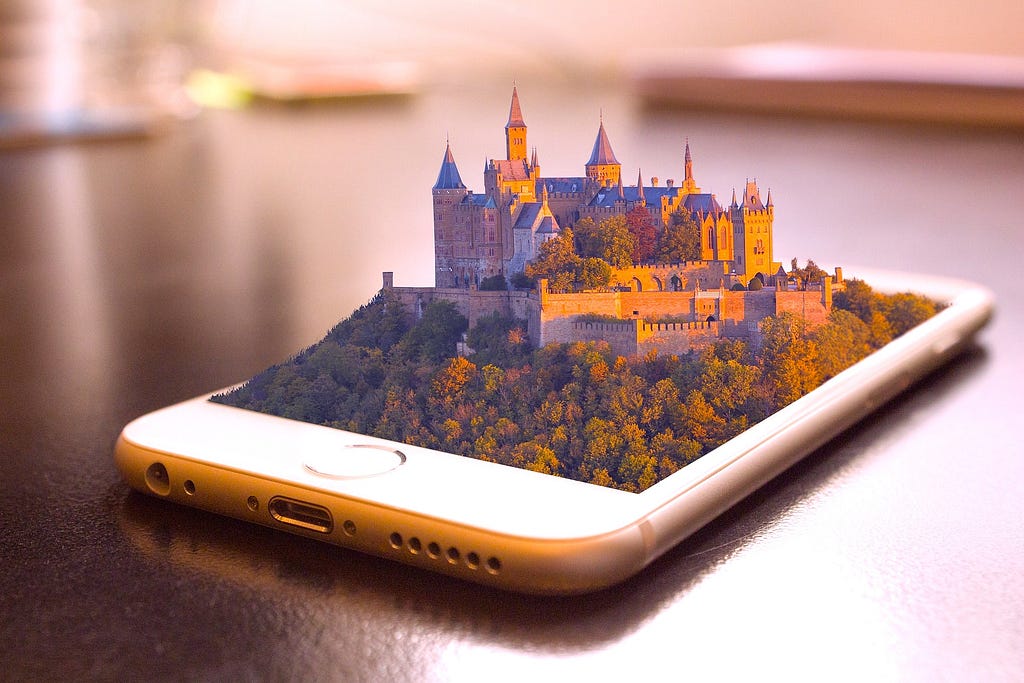 An iPhone laying on the table, with a castle popping out of it’s screen in 3D.