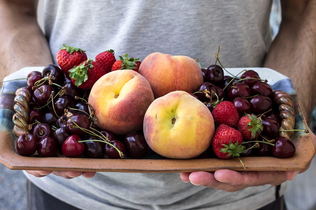 platter with summer fruit: peaches, cherries, berries