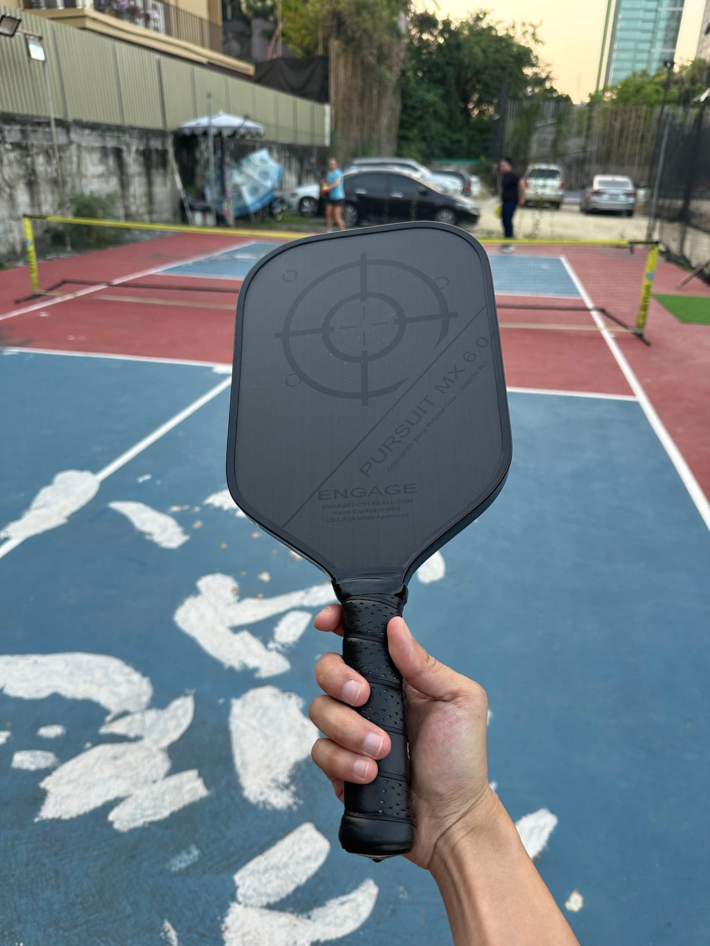 Holding a pickleball paddle at the outdoor pickleball court in Bangkok.