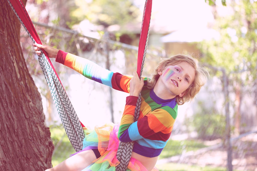 Photo of nonbinary child on swinging on a tree