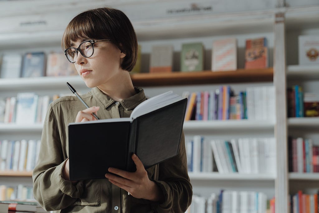 Capa onde a mulher escreve em um caderno dentro de uma livraria