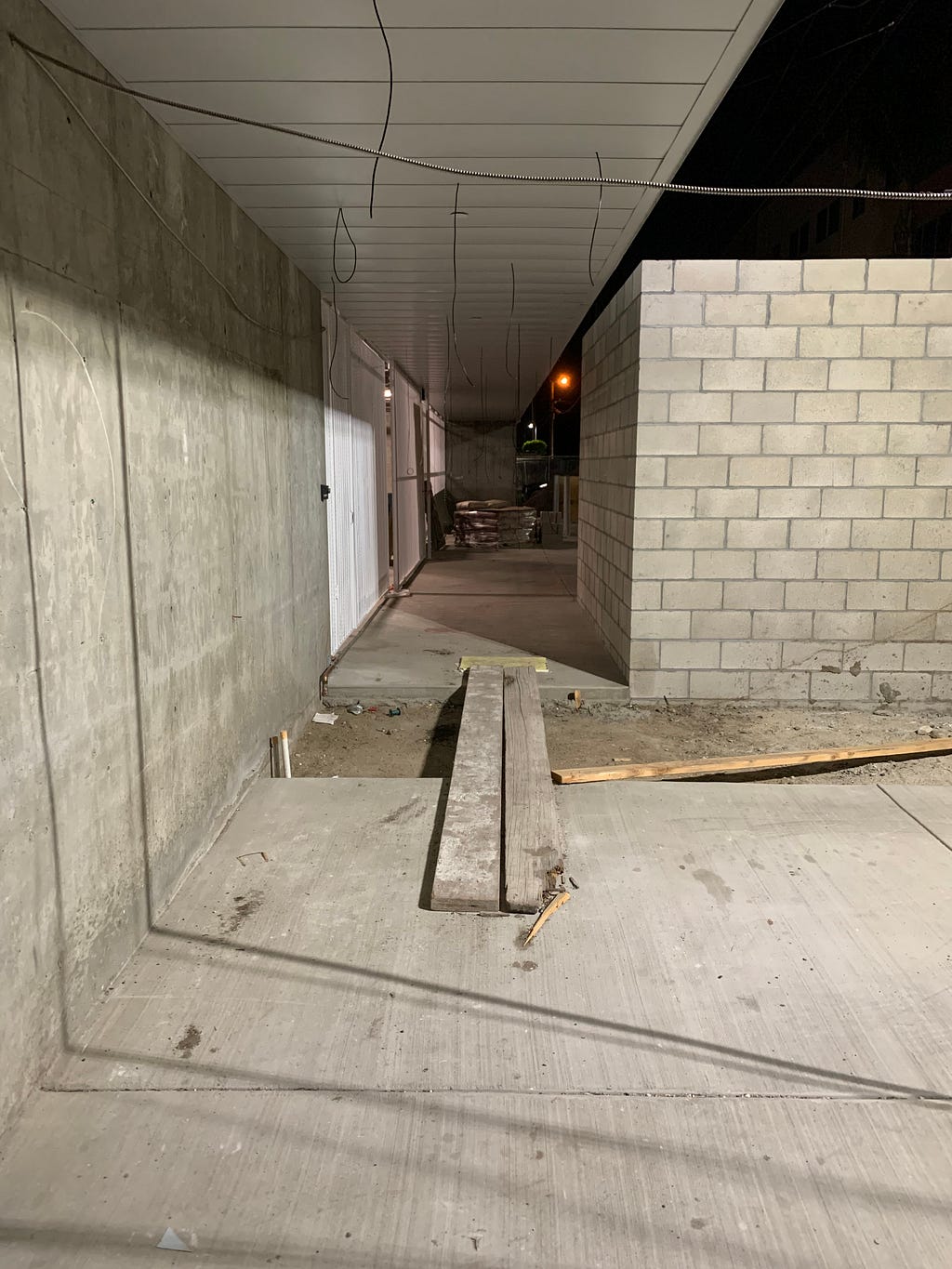 two wooden planks extend over concrete with wires hanging down from the ceiling.