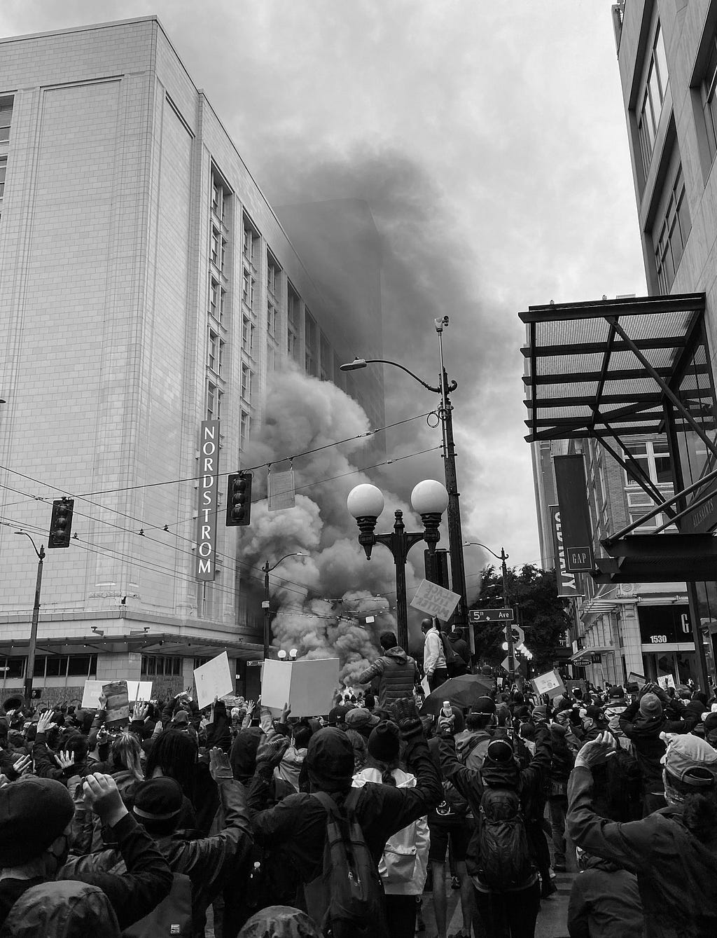 A black and white photo of the World Trade Organization protest in Seattle . The photo is taken in front of Nordstrom Department Store.