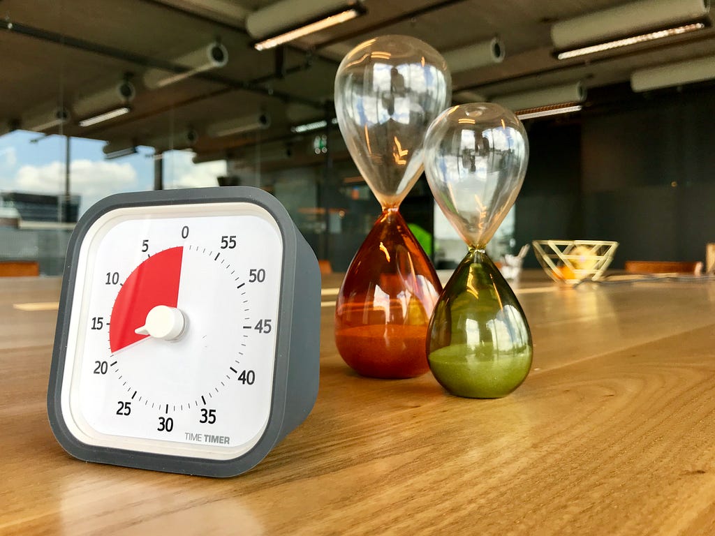 TimeTimer and two hourglasses on a table.