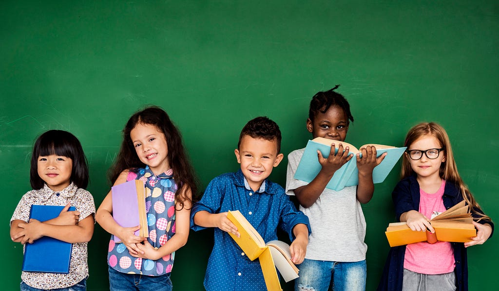 Five children holding books stand against a green background