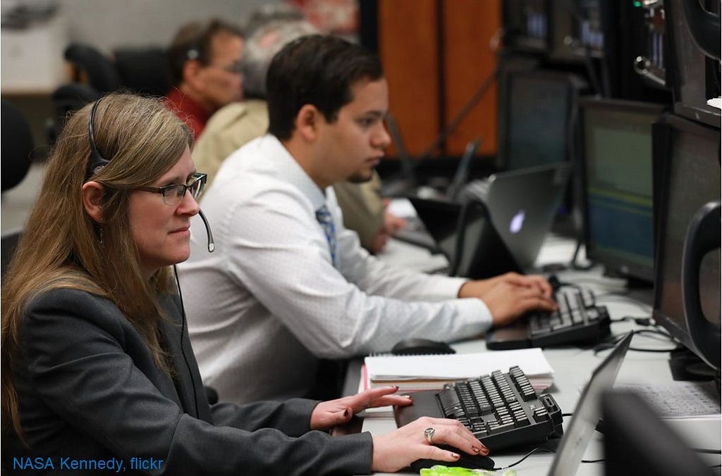 People working at computers with headsets on.