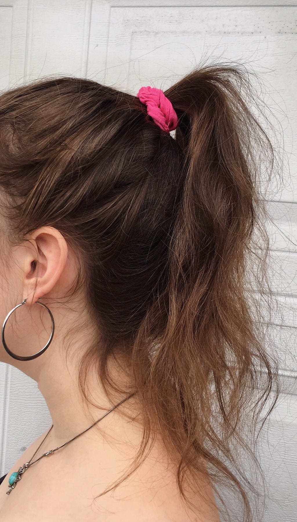 Me wearing a small pink scrunchie in my hair in a high ponytail.
