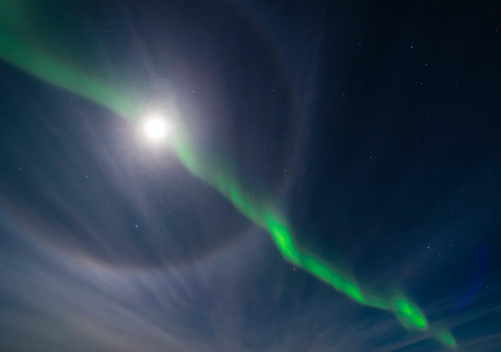 Green Aurora crossing through full moon