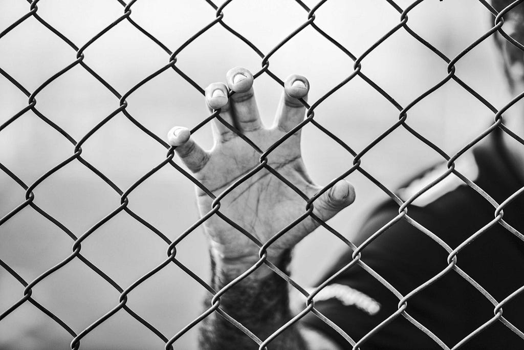 Picture of a mans hand grabbing onto a fence.