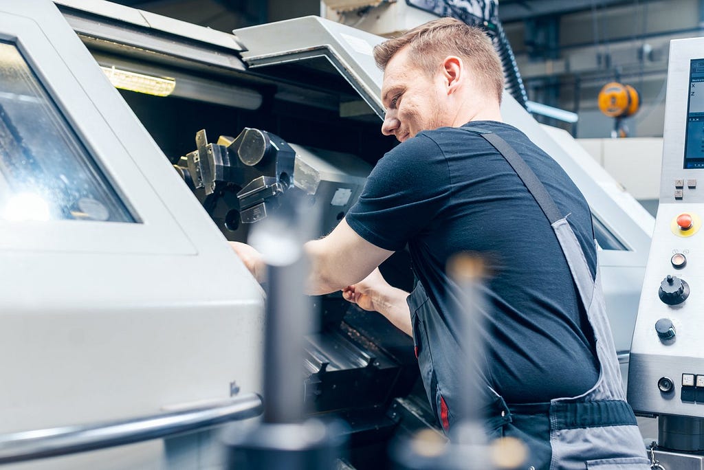 A technician configures a manufacturing machine for faster and higher quality plastic injection molding, increasing the quality of the final product.