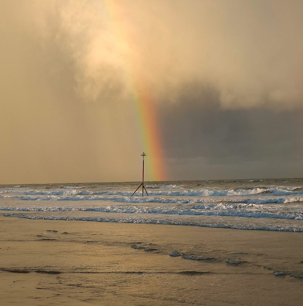 Stormy horizon over sea rainbow in centre over post in waves