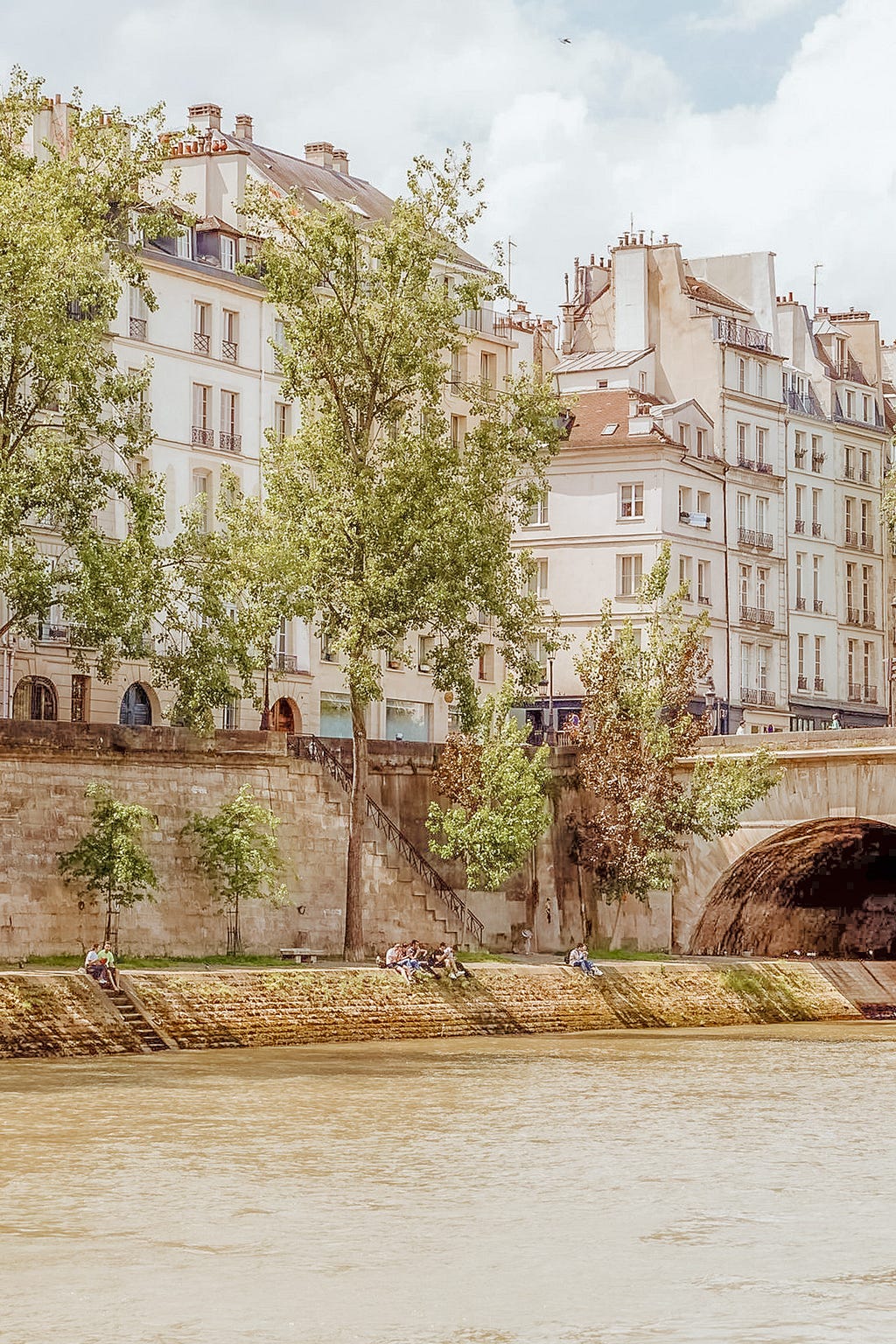 tall buildings on the seine river in paris with people on riverbank