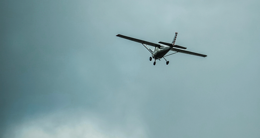 Photo of a small airplane flying into dark clouds.