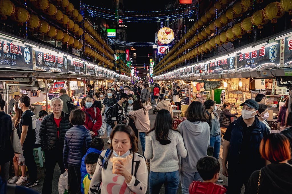 crowded and bustling night market in Keelong Taiwan with the iconic lantern decoration on either side of the street above the food vendor stalls