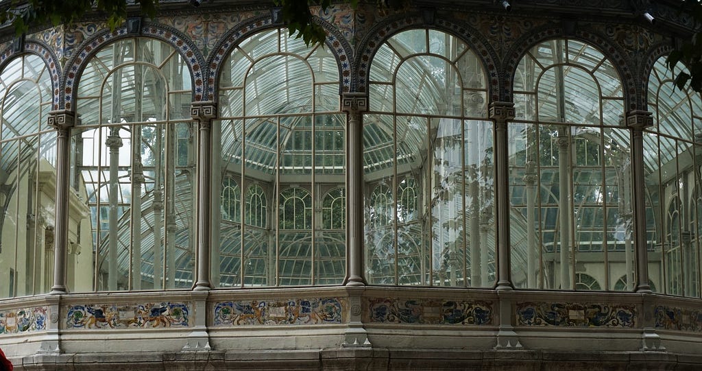 Photo of the facade of the Palacio de Cristal, of four glass big windows, showing the inside of the building.