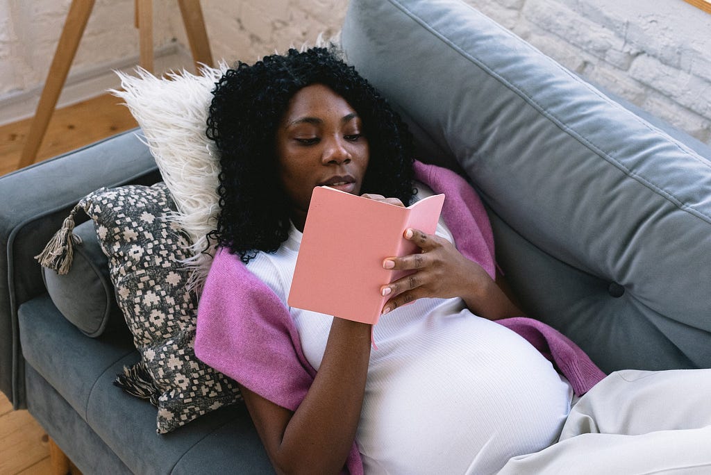 Pregnant women writing in a diary while lying on a couch