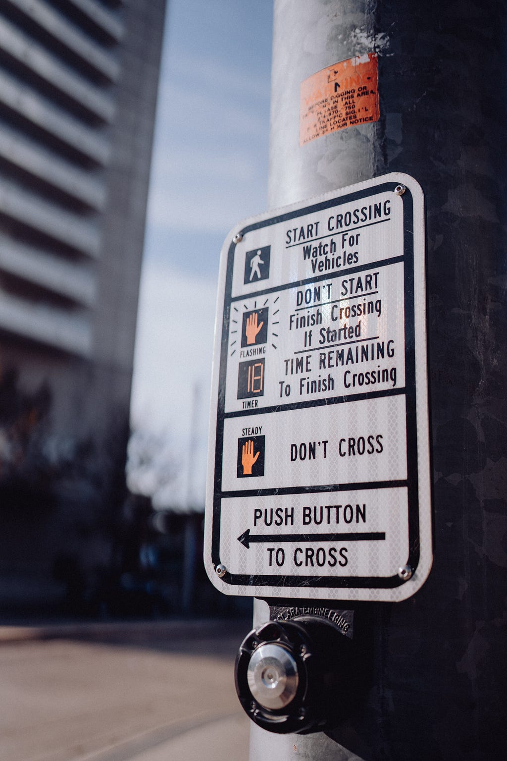 Image of a crossing button with several instructions to cross: Start crossing watch for vehicles; don’t start; and don’t cross. There is also a sign that say “push button.”