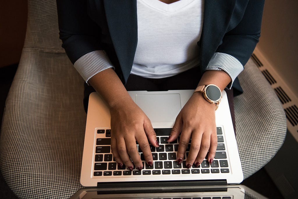 A person’s torso and hands are shown typing on a laptop.