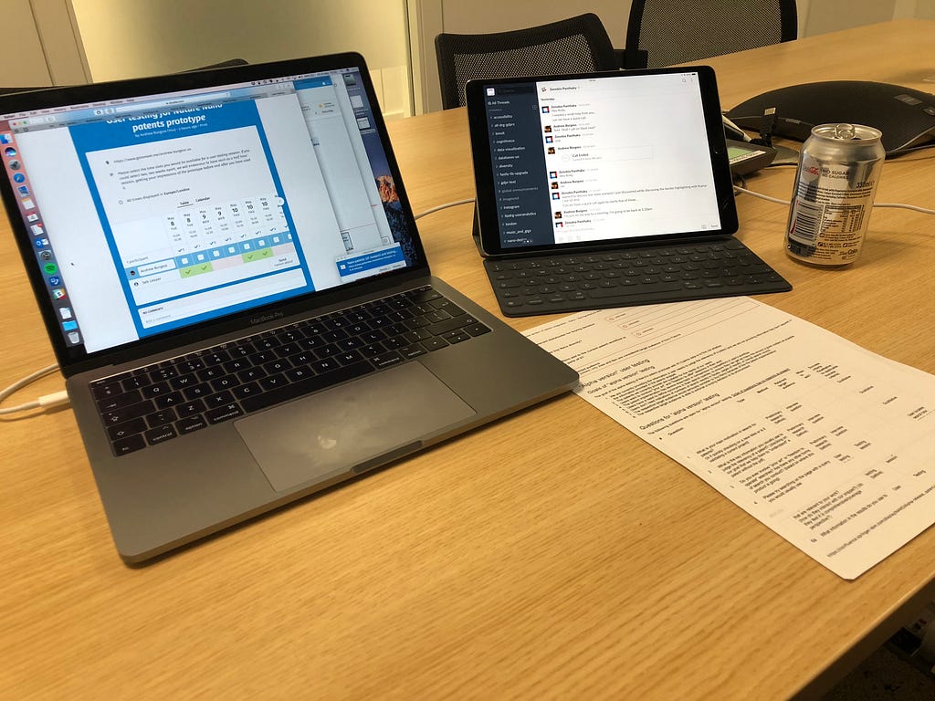 A laptop on the left hand side of a desk, conducting a call with the user, and an iPad with a keyboard on the right hand side, with a chat interface with my team, and a list of printed questions in front of them.