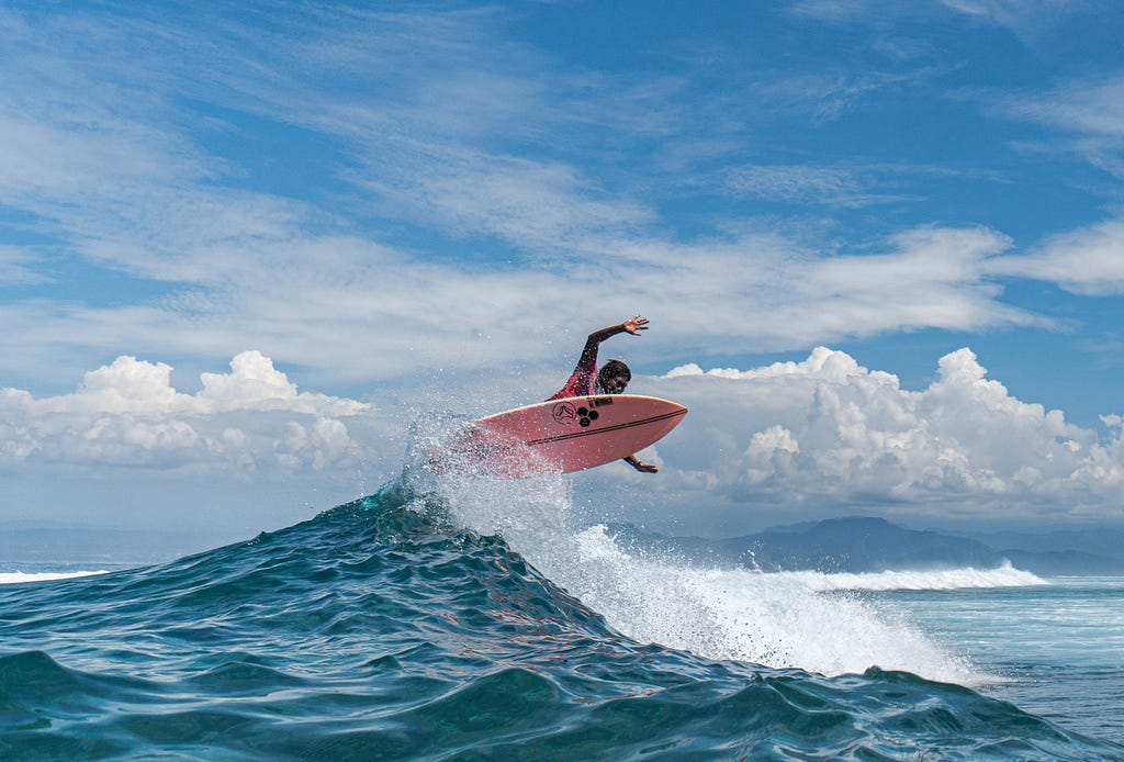 A black surfer practicing extreme sport above ocean waves.