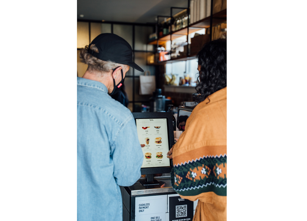 Greg Cornes with customer using Host kiosk in cafe
