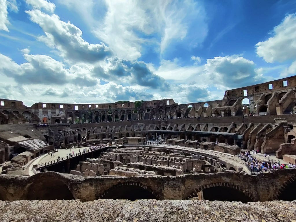 The Colosseum in Rome on a sunny day with blue skies and fluffy white clouds