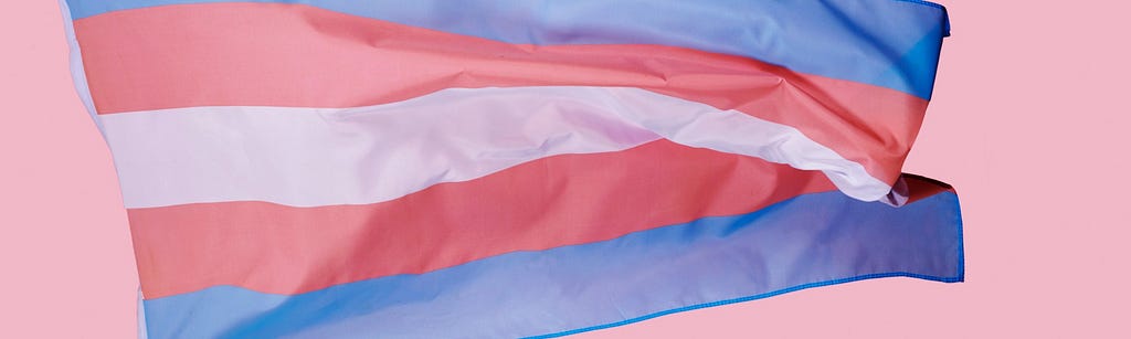 Image of the transgender flag with blue, pink and white horizontal stripes waving.