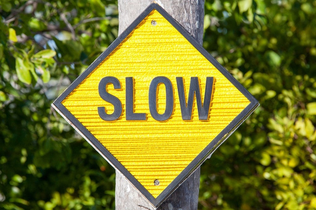 A yellow sign that reads “SLOW” affixed to a pole