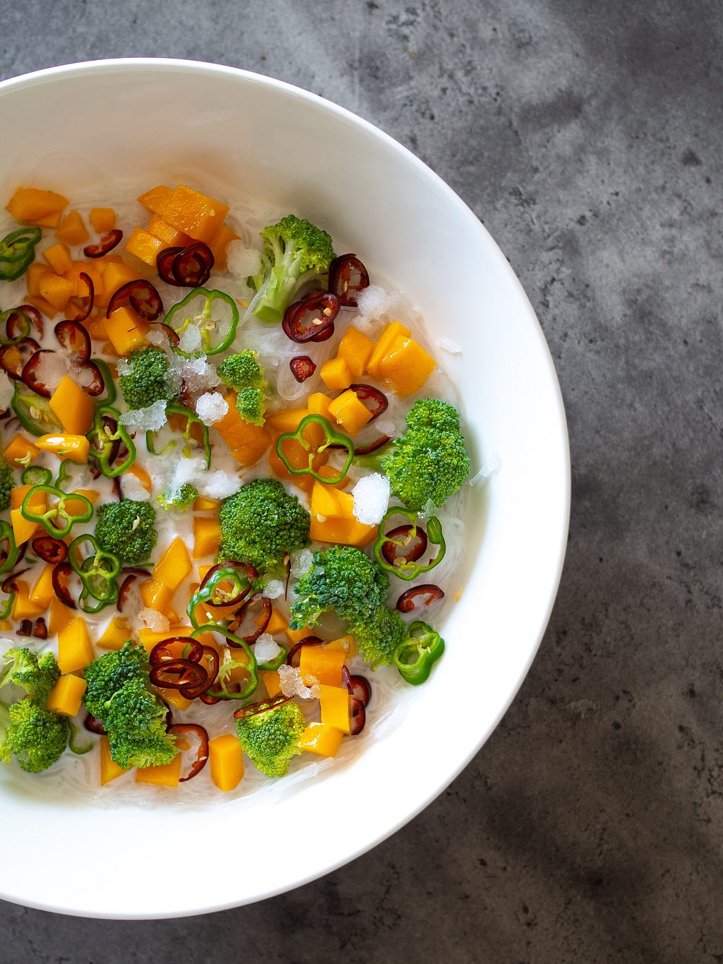 Broccoli, carrots and peppers in a bowl filled with ice.