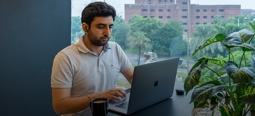A man working at Daftarkhwan | One, with a view of LUMS.